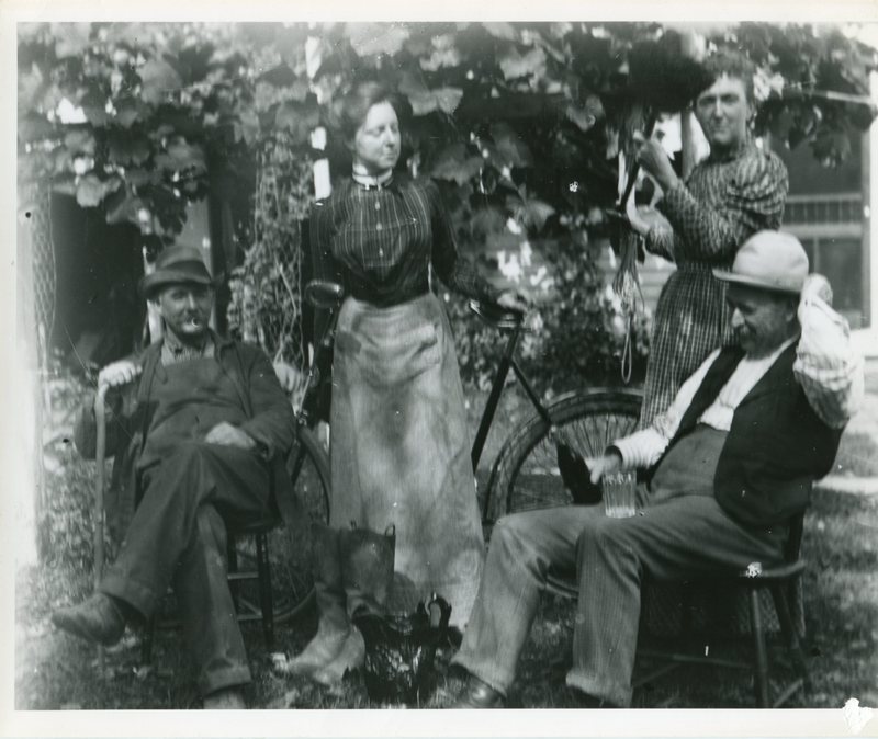 Men seated, women standing by bicycle.jpg