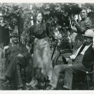 Men seated, women standing by bicycle.jpg